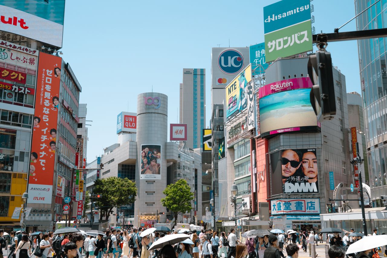 Vue animée du carrefour de Shibuya, très fréquenté, avec ses panneaux publicitaires et ses gratte-ciel à Tokyo, offrant une scène urbaine dynamique.